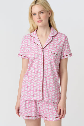 The Hathi Polo Pajamas feature white elephants outlined in red on a pink background, arranged in diagonal rows. Each stylized elephant has a red dot for an eye. Inspired by the Hathi print and made in Peru.