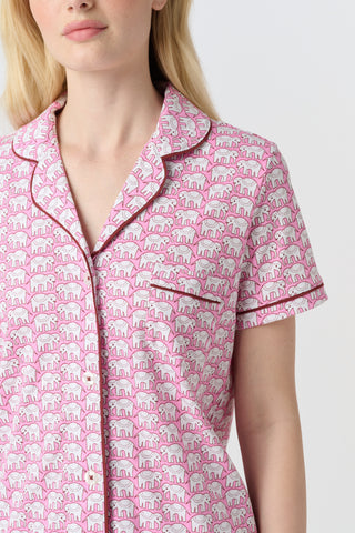 The Hathi Polo Pajamas feature white elephants outlined in red on a pink background, arranged in diagonal rows. Each stylized elephant has a red dot for an eye. Inspired by the Hathi print and made in Peru.