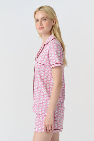The Hathi Polo Pajamas feature white elephants outlined in red on a pink background, arranged in diagonal rows. Each stylized elephant has a red dot for an eye. Inspired by the Hathi print and made in Peru.