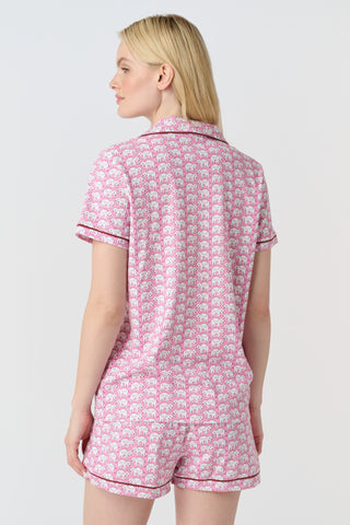 The Hathi Polo Pajamas feature white elephants outlined in red on a pink background, arranged in diagonal rows. Each stylized elephant has a red dot for an eye. Inspired by the Hathi print and made in Peru.