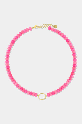 The Beaded Charm Necklace by Roller Rabbit features round pink beads and a small gold ring centerpiece, completed with a gold adjustable clasp and chain. This semi-precious stone necklace is shown against a plain white background.