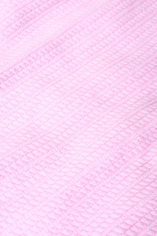 Close-up of the Laine Cardigan by Roller Rabbit in cotton candy pink, featuring a diamond-patterned weave and soft, textured surface for a visually appealing and tactile look.