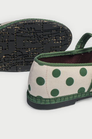 The FLABELUS Polka Dot Pierre is a cream Mary Jane flat with green trim, a green strap featuring a gold buckle, and polka dots—part of the Flabelus collaboration.