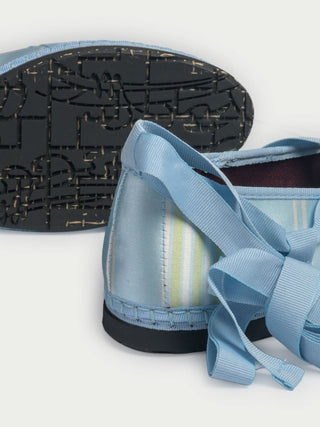 The Positano Stripe Ribbon by FLABELUS is a light blue satin ballet-inspired slipper featuring yellow and white stripes, a pointed toe, blue ankle-wrapping ribbon tie, and a woven sole with visible stitching.