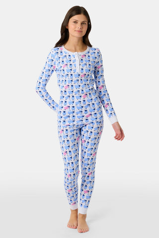 A girl stands barefoot, wearing Roller Rabbit's Kids Sammy The Sheep Pajamas—a matching long-sleeve set with blue and pink sheep patterns on white. She has long brown hair and a neutral expression.