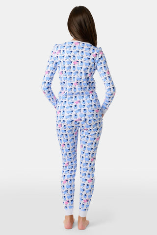 A girl stands barefoot, wearing Roller Rabbit's Kids Sammy The Sheep Pajamas—a matching long-sleeve set with blue and pink sheep patterns on white. She has long brown hair and a neutral expression.