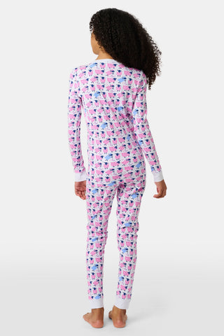A smiling young girl stands barefoot in Kids Sammy The Sheep Pajamas by Roller Rabbit, posing against a white backdrop to showcase stylish children's sleepwear.