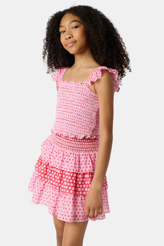 A young girl wears the Roller Rabbit Kids Starry Dot Tory Top in pastel pink with flutter sleeves, paired with a matching skirt featuring red stars and white polka dots. Only her torso and part of her face are visible.