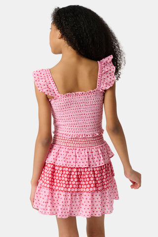 A young girl wears the Roller Rabbit Kids Starry Dot Tory Top in pastel pink with flutter sleeves, paired with a matching skirt featuring red stars and white polka dots. Only her torso and part of her face are visible.