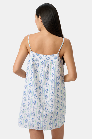 A woman models the Roller Rabbit Rosa Wavy Stripe Scottie Dress, a sleeveless white sundress with thin straps and blue wavy stripe patterns, standing facing forward against a plain light background.