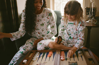 Two people in matching pajamas playing backgammon in a cozy room. Roller Rabbit