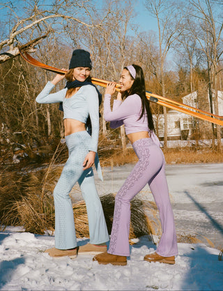 Two women posing with a large orange object in a snowy landscape.