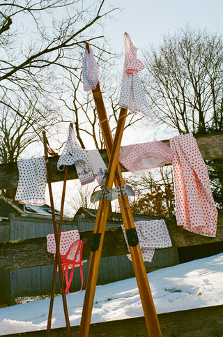 Roller Rabbit Print. Fabric items hanging on a wooden frame against a snowy landscape with trees.