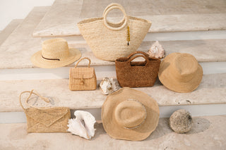 Collection of straw hats and bags on a wooden surface with seashells.