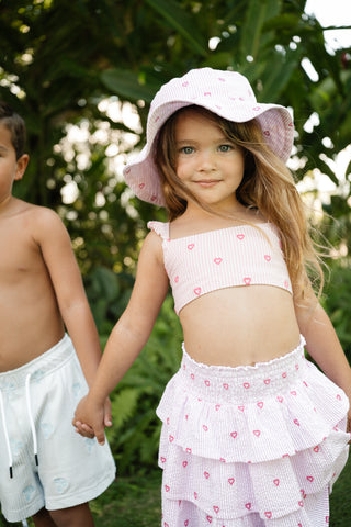 Girl standing in her roller rabbit seersucker swimwear, skirt, and matching bucket hat.