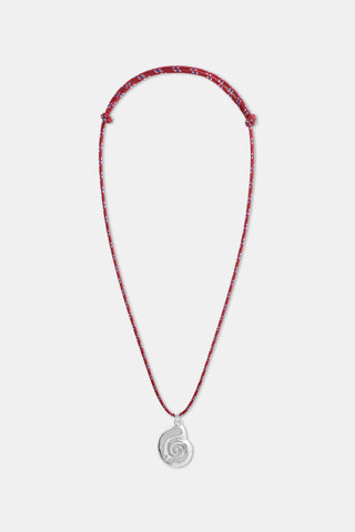 A woman, shown from the lower face down, wears a white button-up shirt and the Roller Rabbit Swirl Cord Necklace with a bold red cord and an eye-catching silver shell pendant.