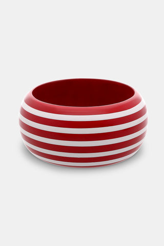 The Roller Rabbit Striped Bangle is a wide, round wooden bracelet with a glossy red finish and evenly spaced hand-painted white stripes, shown on a plain light gray background.