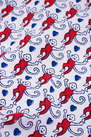 A woman stands with hands behind her back in Roller Rabbit's Campus Lovely Monkey Polo Pajamas, a short-sleeved, button-up red and navy romper with playful patterns—perfect sleepwear for showing your school spirit.