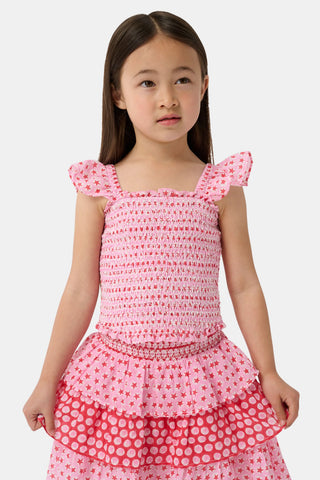 A young girl wears the Roller Rabbit Kids Starry Dot Tory Top in pastel pink with flutter sleeves, paired with a matching skirt featuring red stars and white polka dots. Only her torso and part of her face are visible.