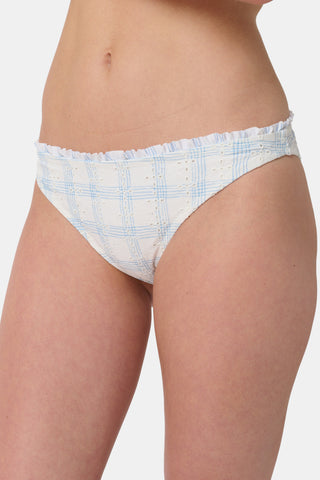 A person wearing the Roller Rabbit Sun Check Eyelet Sydney Bikini Bottom, featuring blue gingham with ruffled edges, is shown from mid-torso to upper thigh against a plain background.