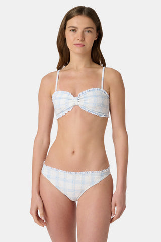 A person wearing the Roller Rabbit Sun Check Eyelet Sydney Bikini Bottom, featuring blue gingham with ruffled edges, is shown from mid-torso to upper thigh against a plain background.