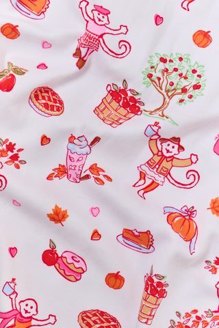 A woman stands barefoot against a plain white background, hands in pockets, wearing the Roller Rabbit Sweater Weather Long Sleeve Polo Pajamas—a floral pink and white set featuring a long-sleeved polo top and matching pants.