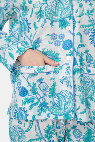 The Amanda Loungewear pajama set features white cotton fabric adorned with blue and turquoise floral and botanical patterns, adding a charming, intricate touch to women’s sleepwear.