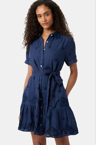 A woman models the Roller Rabbit Vanna Embroidery Margaret Dress—a short-sleeve navy linen shirtdress with a belted waist—standing against a plain light background.