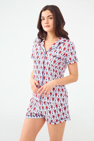 A woman stands with hands behind her back in Roller Rabbit's Campus Lovely Monkey Polo Pajamas, a short-sleeved, button-up red and navy romper with playful patterns—perfect sleepwear for showing your school spirit.