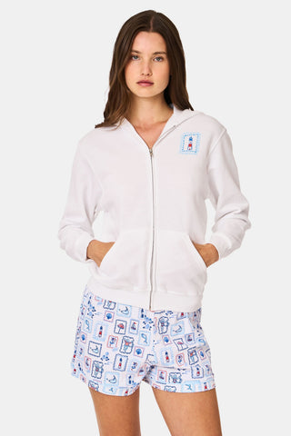 A person wearing the Roller Rabbit ACK Zip Up hoodie, featuring a blue and red nautical design on the back, paired with patterned shorts and standing with their back to the camera and hood up.