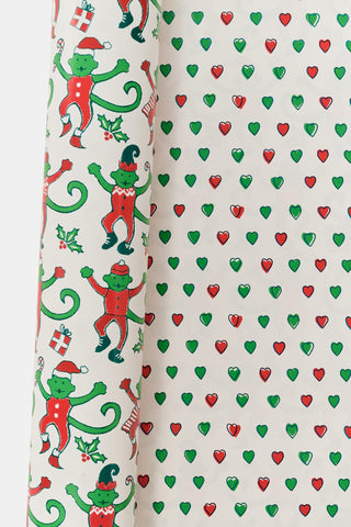 Monkey Mas/Holiday Hearts Wrapping Paper featuring a pattern of green monkeys in Santa hats and outfits on one side, and a pattern of small Holiday Hearts on the other.