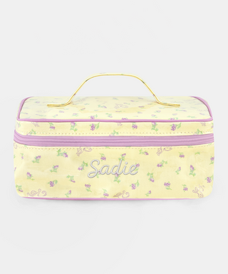 The Roller Rabbit Mini Monkey Blossom Carry All Case is a rectangular yellow toiletry bag featuring a pink floral pattern, a purple zipper, and a yellow handle on top. Displayed against a plain white background, this stylish travel bag is perfect for organizing your essentials.