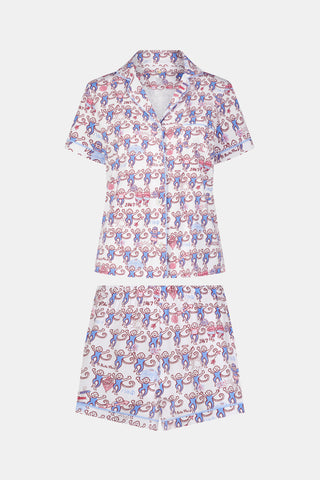 The Roller Rabbit Pi Beta Phi Monkey Polo Pajamas feature a short-sleeved button-up top and matching shorts, adorned with a playful pink and blue monkey print on a white background. Crafted from soft Pima cotton with an elastic waistband for comfort, these pajamas are made in Peru.